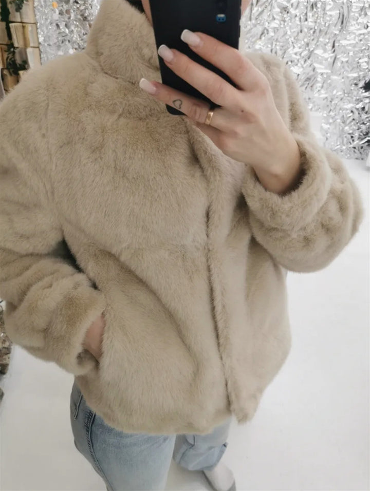 Fleece jacket for women with stand-up collar and side pockets with openings.