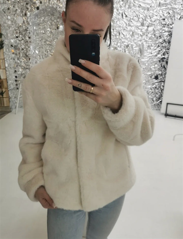Fleece jacket for women with stand-up collar and side pockets with openings.