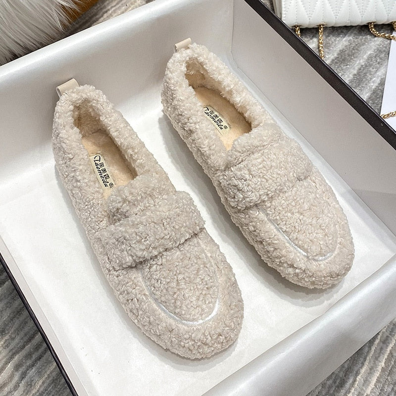 Ein Paar cremefarbene Plüsch-Pantoffel-Schuhe