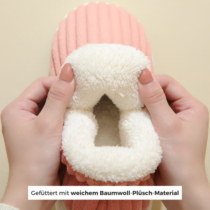 Hände, die warme pink hausschuhe vorführen