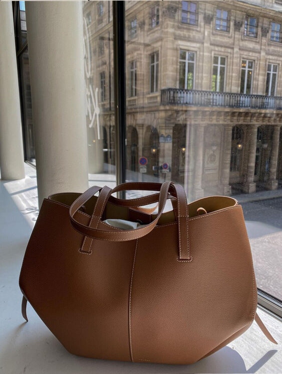 Braun ledertasche auf einem fensterbrett, mit blick auf ein klassisches gebäude draußen
