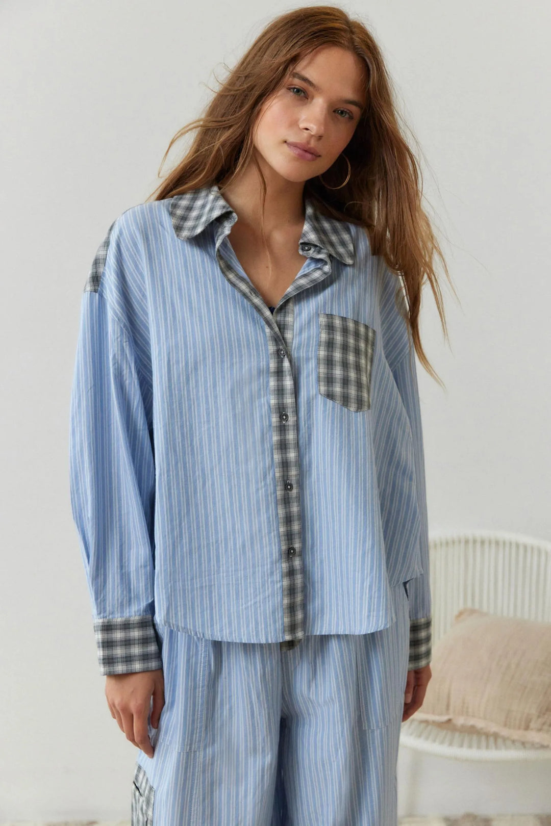 Eine Frau trägt ein 2-teiliges blaues, lässiges Pyjama-Set mit Karomuster
